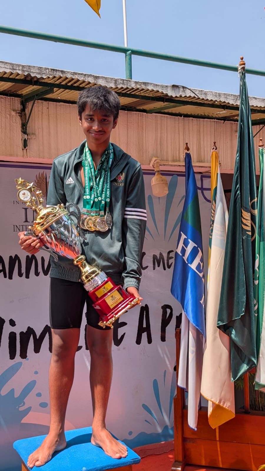 Zachary on the podium holding a trophy, wearing his medals